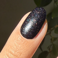 The Celestial Effect Top Coat adding a shimmering starry sparkle finish over a dark manicure on a natural nail. thumbnail