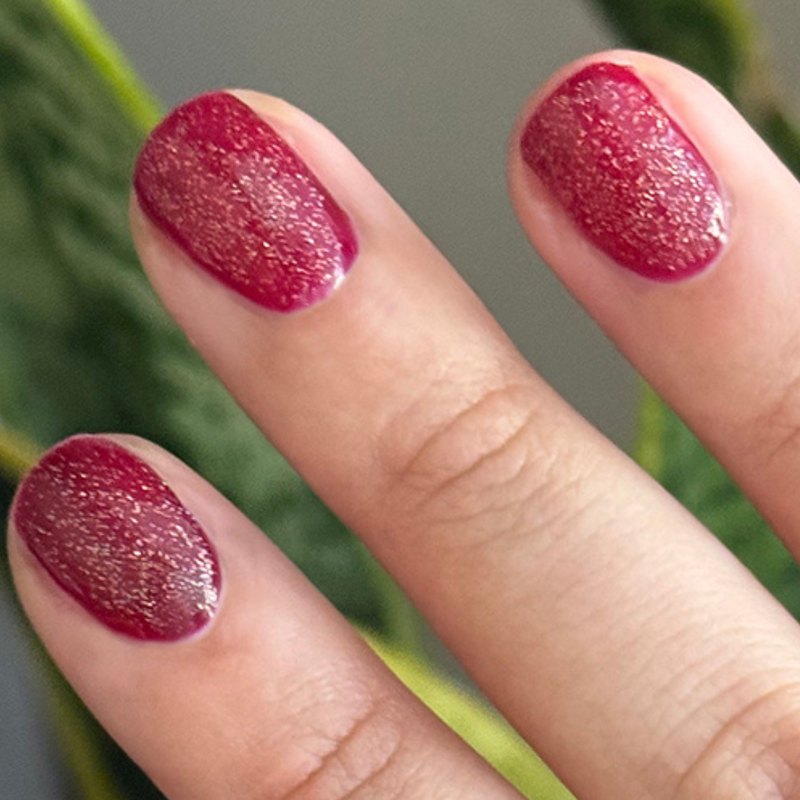 The Celestial Effect Top Coat adding delicate sparkly micro-shimmer over red polish for a luminous manicure finish
