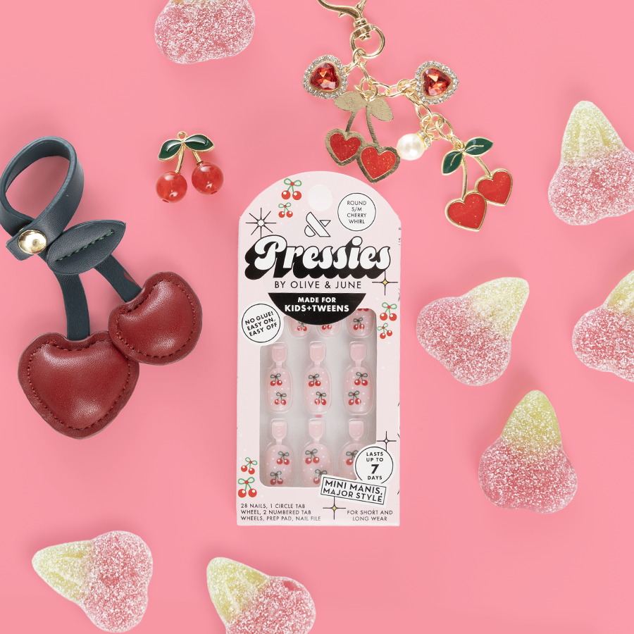 Cherry Whirl - Pressies | Short Medium | Round showing cherry-themed press on nails in packaging on pink background with cherry accessories