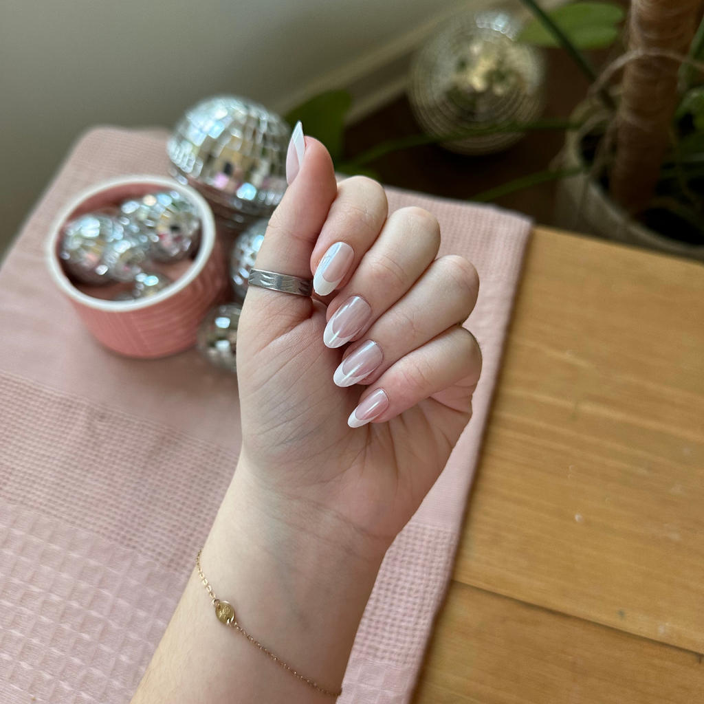 Chrome French - Press-On | Medium | Oval showing glossy medium oval false nails with thick white french tips on hand indoors