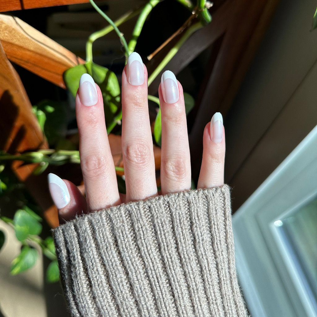 Chrome French - Press-On | Medium | Oval showing a natural hand with medium oval press-on nails and classic thick white french tips outdoors