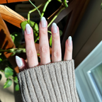 Chrome French - Press-On | Medium | Oval showing a natural hand with medium oval press-on nails and classic thick white french tips outdoors