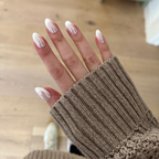 Chrome French - Press-On | Medium | Oval showing medium oval false nails with thick white tips on hand wearing brown knit sweater indoors