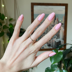 Hand with almond-shaped nails painted in Crown shimmery princess pink gel polish showing a smooth manicure indoors