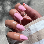 Hand with almond-shaped nails painted in Crown shimmery pink gel polish showing a glossy at home manicure in natural light