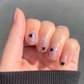 Valentine Mini Polish Set nails with sheer nude base, black speckles, and black heart accents for a subtle mani look thumbnail
