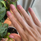 World Lit - Press-On | Extra Short | Round showing hand with mauve extra short round press-on manicure in natural light indoors