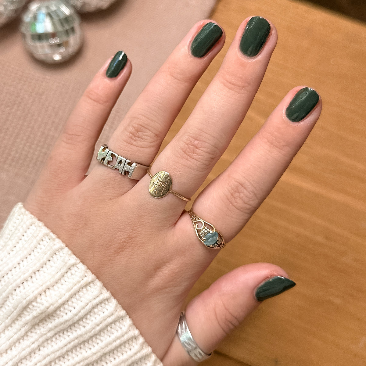 Hand displaying glossy nails painted in One For You, Two For Me gel polish by Olive and June in dark emerald green