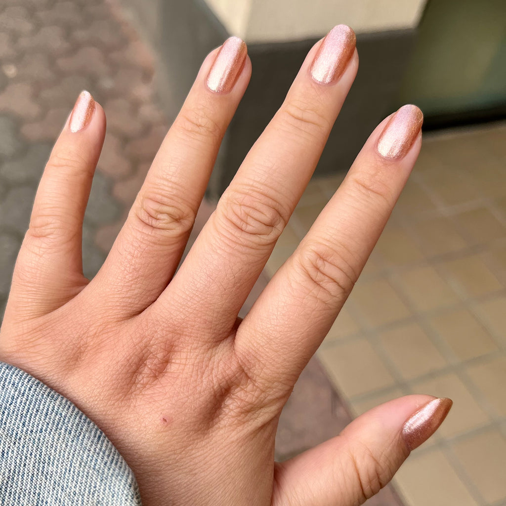 Hand with Penny polish showing smooth shiny copper metallic manicure on natural skin with neutral background