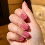 Hand with Primrose gel polish in warm rosey pink showing glossy nails and natural light on medium skin tone