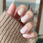 Classic French | Short | Round - Tab Press-On nails with soft white tips shown on hand wearing cozy knit sweater indoors