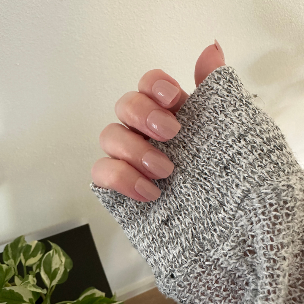 Poodle | Extra Short | Squoval - Tab Press-On nails in neutral beigey pink polish on hand wearing gray knit sweater indoors