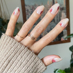 Layered Circles - Press-On | Medium | Oval oval neutral nails with burnt orange and white swirl accents on hand wearing cozy knit sweater