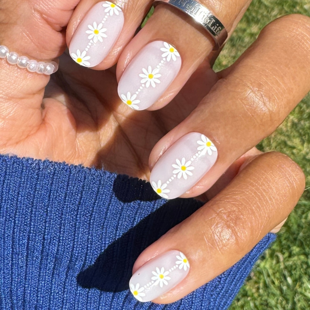 Daisy Chain - Press-On | Short | Round featuring short round nails with delicate white daisy design on sheer neutral base outdoors