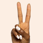 Daisy Pop | Short | Round - Tab Press-On featuring short round neutral nails with white daisy floral design on hand showing peace sign