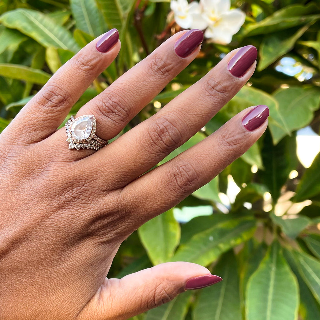 Hand with medium-length nails polished in Don’t Spill on the White Couch deep dusty berry red gel polish outdoors