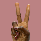 Hand showing peace sign with short nails polished in Don’t Spill on the White Couch deep dusty berry red gel polish manicure