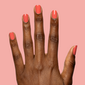 Hand with nails painted in glossy bright coral red using Field Day - Gel against soft pink background thumbnail