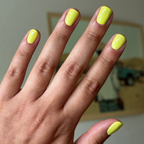 Hand with nails painted bright electric yellow Game Set Mani polish for a glossy quick-dry manicure look at home
