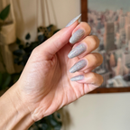 Glitter Department ultra fine holographic silver polish on natural almond-shaped nails for a sparkling manicure look