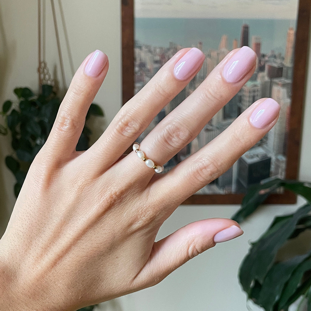 Hand with Glossed gel polish manicure in cool-toned sheer lavender-pink on natural nails indoors