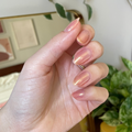 Hand with long natural nails painted in soft shimmering shades using Gold Drops for a delicate manicure display thumbnail