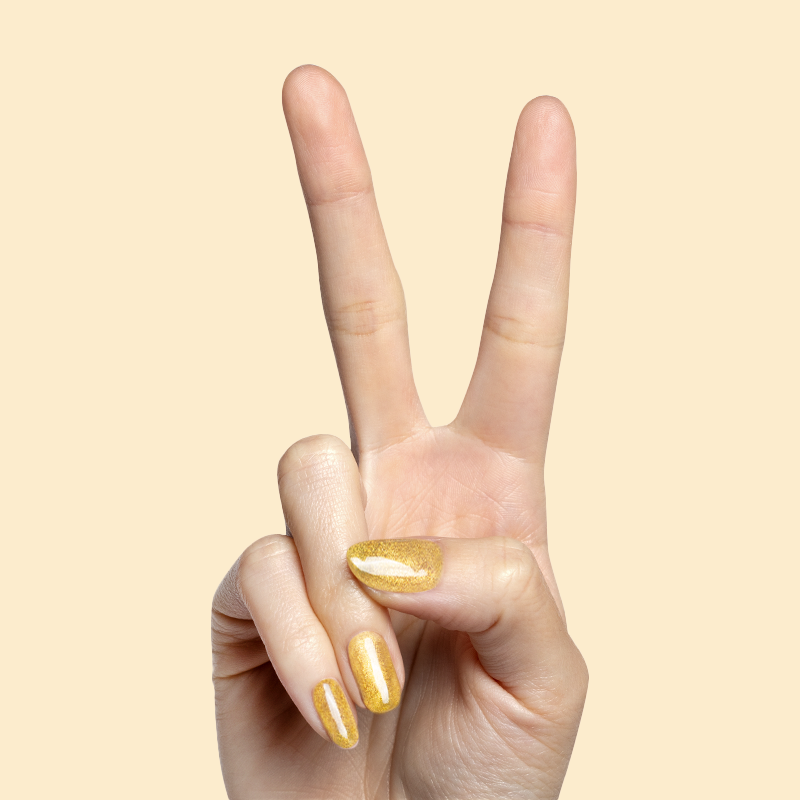 Hand showing peace sign with nails painted in shimmering golden polish from Magnetic Gel Polish Set manicure collection