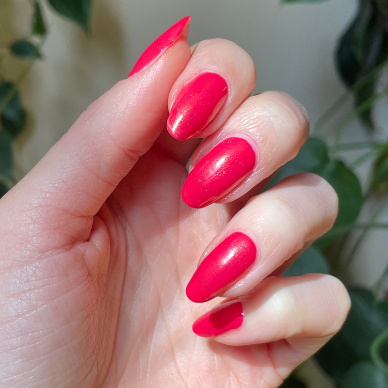 The Golden Effect Top Coat adding a subtle golden glow over vibrant red nails for a long-lasting manicure finish