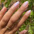 Natural hand with softly glossy nails in pale pink shade featuring The Glazed Mani System manicure finish outdoors thumbnail