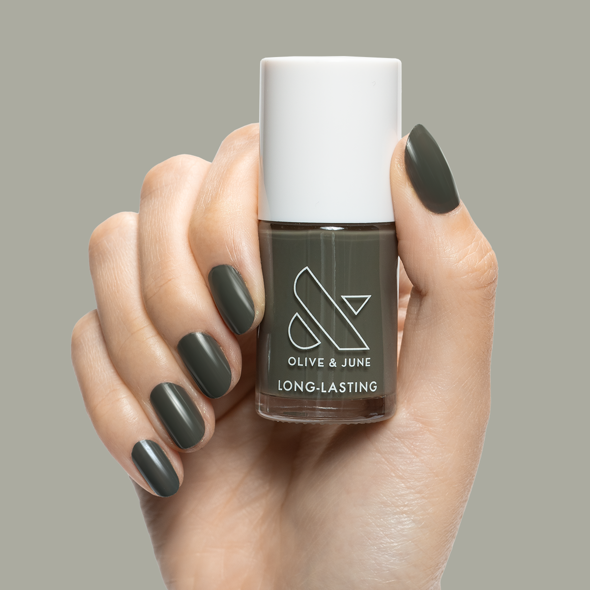 Hand holding "Is it Smoky in Here?" long-lasting gel polish with dark charcoal gray manicure on neutral background