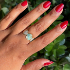 Jammy bright sheer cabernet gel polish on natural nails with glossy finish and spiral gold ring outdoors