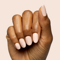 Hand with nails shaped and painted in KAG - Gel neutral peachy pink gel polish on smooth warm beige background thumbnail