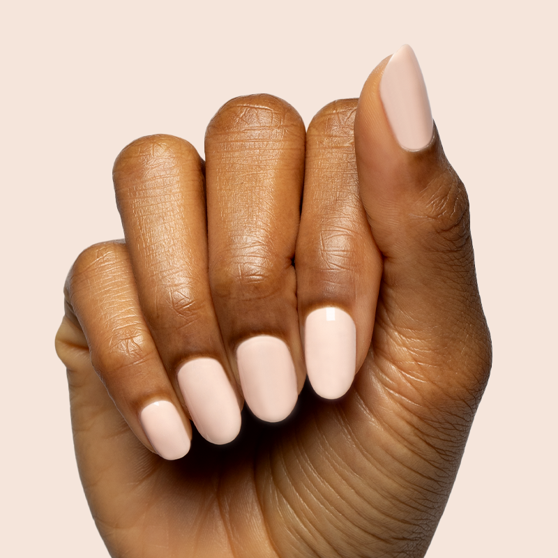 Hand with nails shaped and painted in KAG - Gel neutral peachy pink gel polish on smooth warm beige background