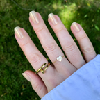 Team Manuscript - Press-On | Short | Squoval showing semi-sheer gold glazed short squoval press-on false nails on hand with rings outdoors