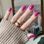 Hand with glossy Leotard quick dry gel polish manicure on medium-length nails wearing gold ring and beige sweater sleeve
