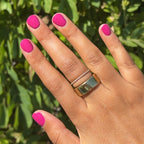 Hand with Leotard quick dry gel polish manicure in vibrant magenta pink on natural nails against green foliage background