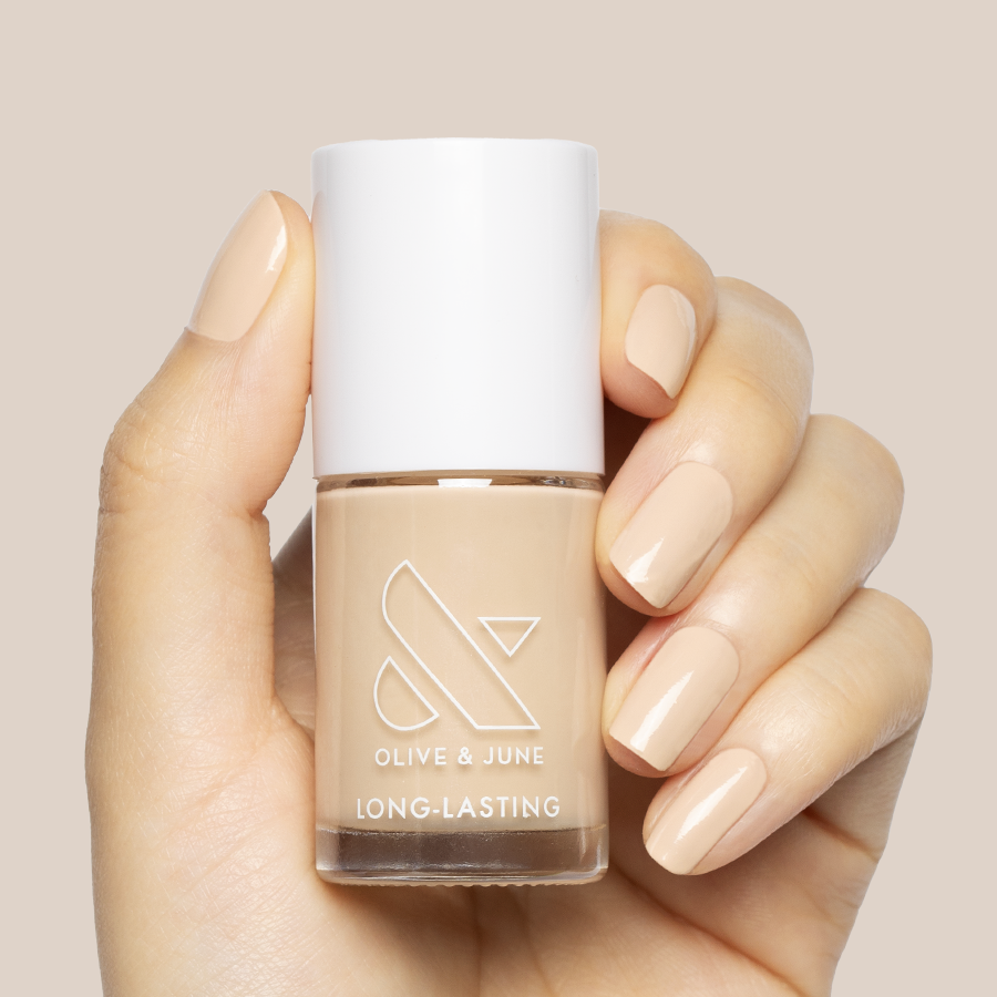 Hand holding Line Dancing Boots polish with nails painted a neutral toasted cream shade for an elegant manicure look