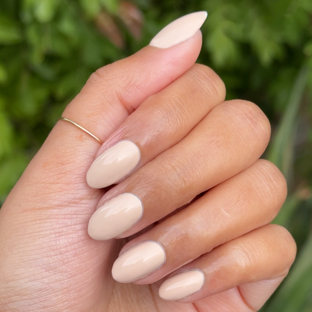 Hand with almond-shaped nails painted in creamy neutral shade using Line Dancing Boots for a smooth manicure finish