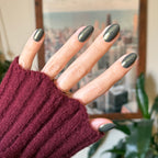 Hand with medium-length nails painted in Martini Chrome gel polish showing deep olive green with golden chrome shimmer manicure