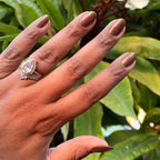 Hand with medium-length nails painted in Milk Chocolate gel polish showing warm brown tone with golden iridescence outdoors