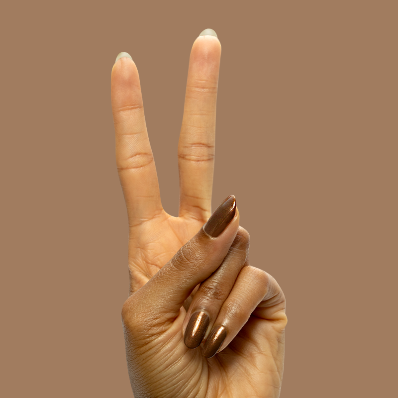Hand displaying peace sign with long nails painted in Milk Chocolate gel polish on brown background