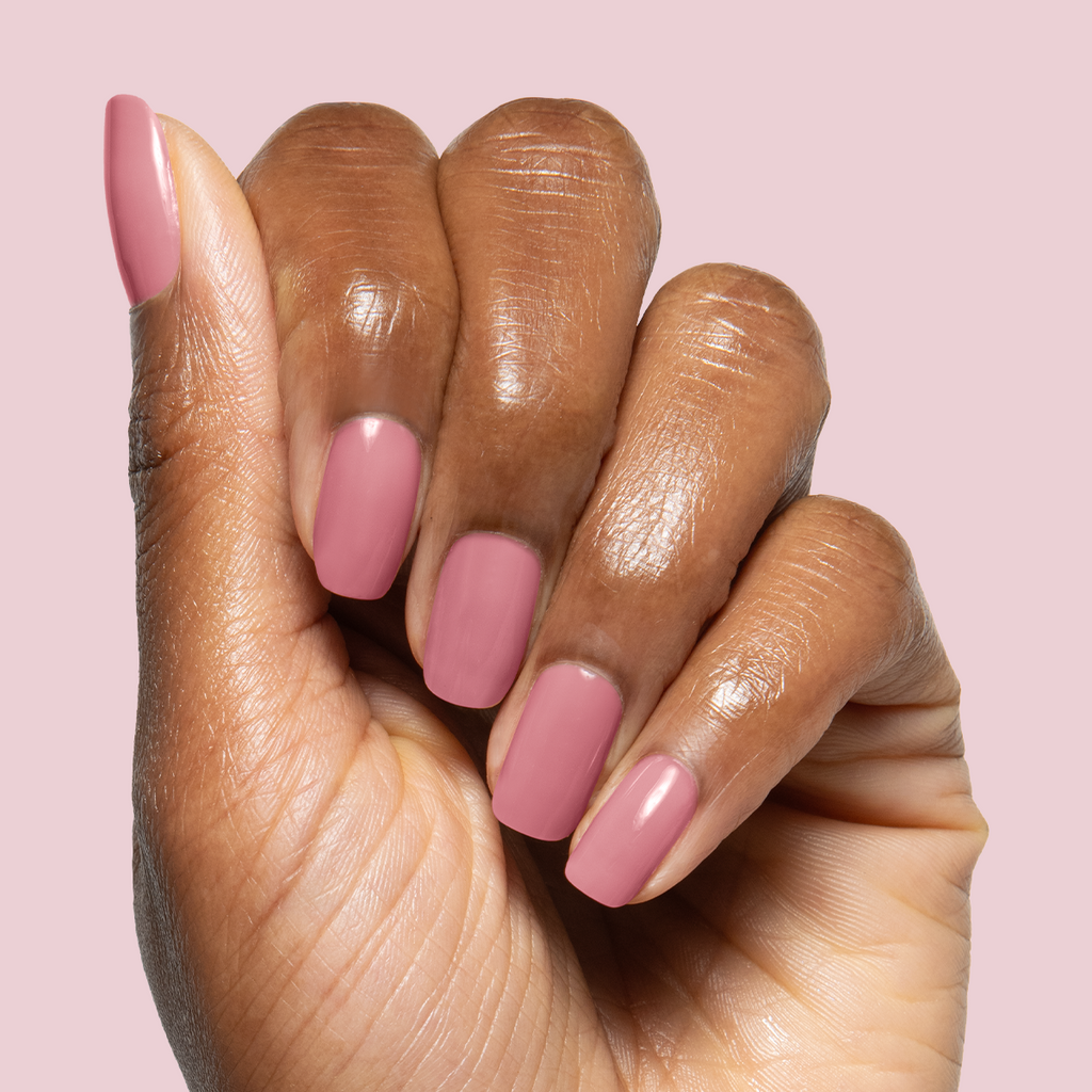 Hand with medium-length nails polished in muted rose shade using Blush Jelly Builder Gel Kit on light pink background