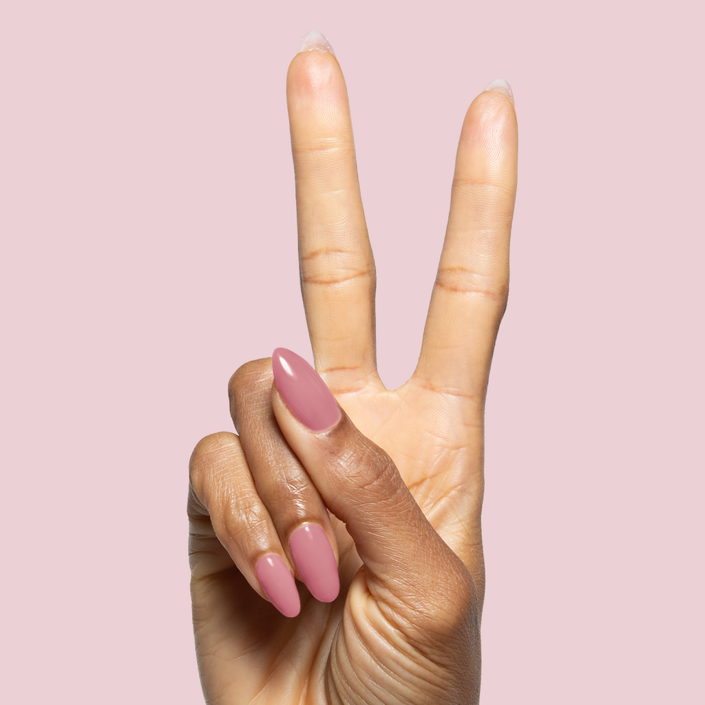 Hand with long nails polished in muted pink using Blush Jelly Builder Gel Kit on soft pink background