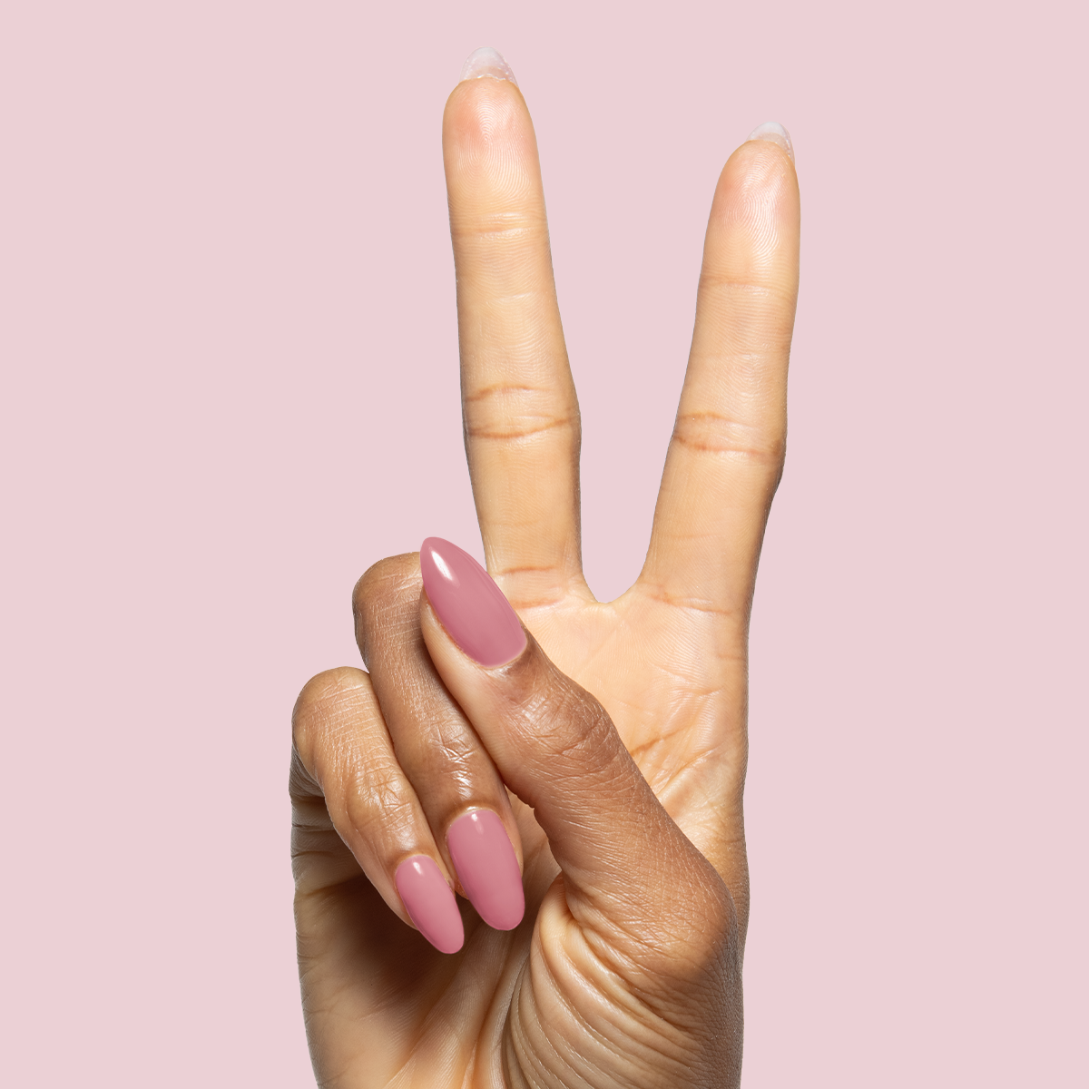 Hand with long nails polished in muted pink using Blush Jelly Builder Gel Kit on soft pink background