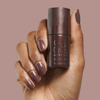 Hand with gel manicure in Goal Getter - Gel, a deep chocolate shade with golden shimmer, holding matching polish bottle