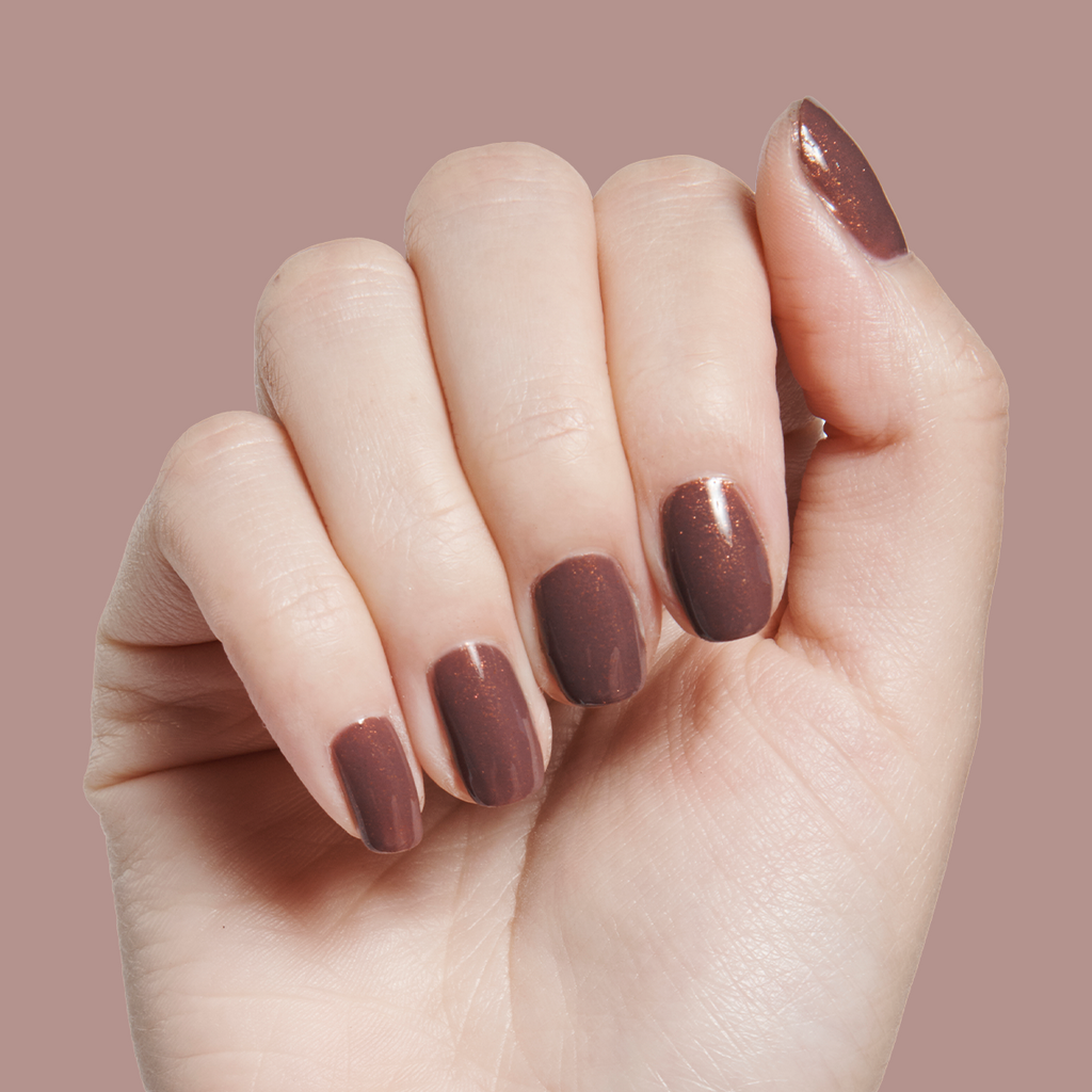 Hand with medium-length nails polished in Goal Getter - Gel, a shimmering chocolatey neutral gel manicure on pale skin