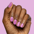 Hand with nails painted in bright floral purple pink shade using Petal - Gel polish on soft purple background thumbnail