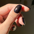 The Pixie Effect Top Coat adding sparkling iridescent shimmer over black polish for a dazzling manicure look thumbnail