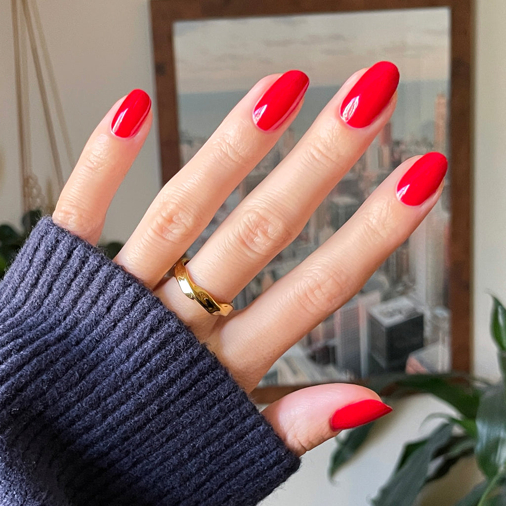 Hand with medium oval nails in Secret Recipe polished manicure against blurred indoor background