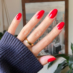 Hand with medium oval nails in Secret Recipe polished manicure against blurred indoor background